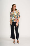 Woman wearing a colorful floral blouse and black pants on a white background