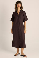 Woman wearing a brown dress against a plain background