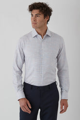 Man wearing a light gray checkered shirt and dark pants on a white background