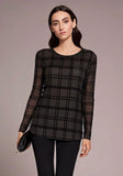 Woman wearing a black plaid top and black pants against a neutral background
