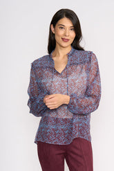 Woman wearing a patterned blouse and maroon pants on a white background