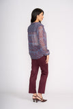 Woman wearing a patterned blouse and burgundy pants on a white background