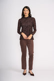 Woman wearing a brown patterned top and matching pants on a white background