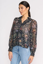 Woman wearing a floral blouse with long sleeves and light blue jeans on a white background
