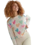 Woman wearing a colorful heart-patterned sweater against a white curtain background