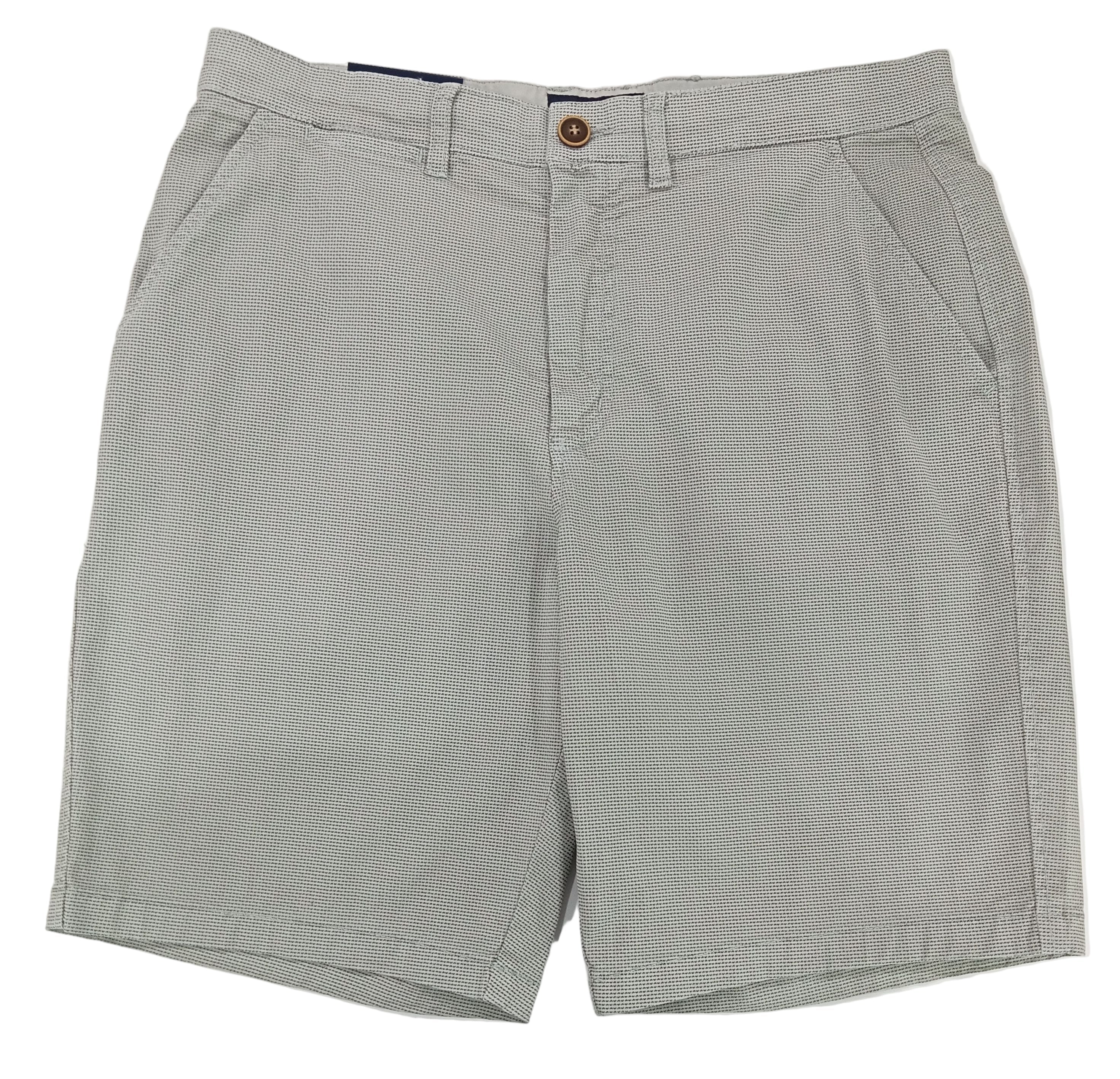 Gray shorts on a white surface with a textured wall background
