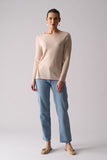 Woman wearing a beige sweater and blue jeans on a plain background
