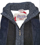 Close-up of a blue jacket with a visible brand tag on a wooden surface