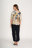 Woman wearing a colorful floral blouse and black pants on a white background