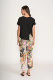 Woman wearing a black t-shirt and colorful floral pants on a white background