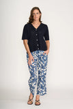 Woman wearing a navy top and blue leaf-patterned pants on a white background
