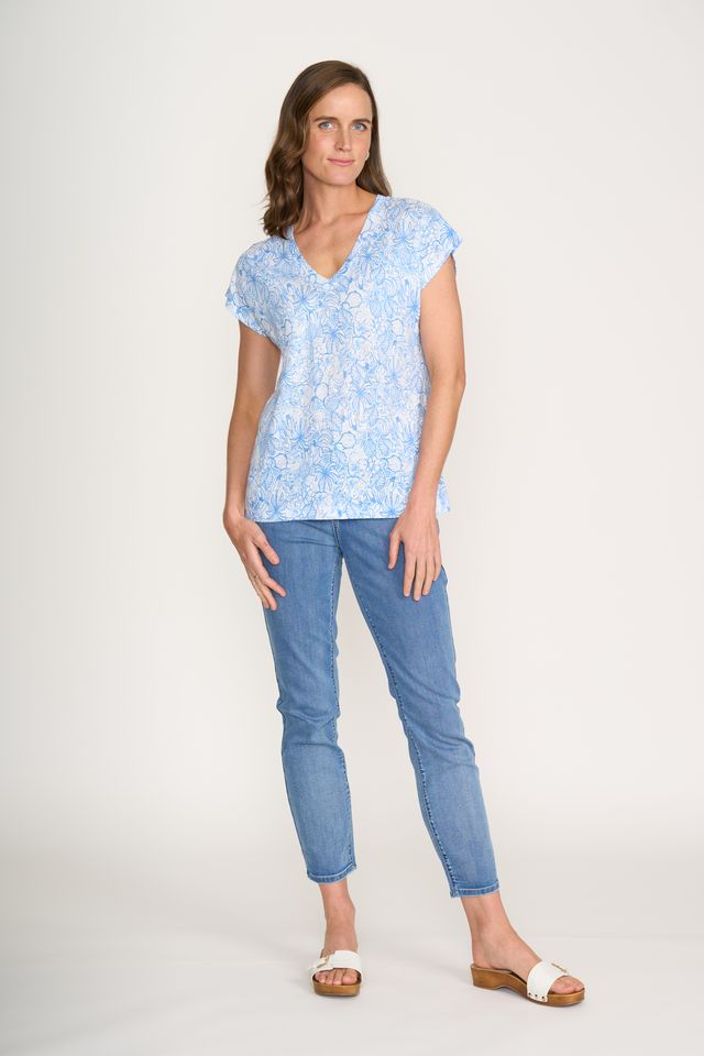 Woman wearing a light blue floral top and jeans on a white background