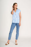 Woman wearing a light blue floral blouse and jeans on a white background