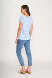Woman wearing a light blue floral top and jeans on a white background