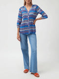 Woman wearing a blue patterned shirt and jeans on a white background