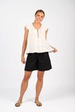 Woman wearing a white sleeveless top and black shorts on a white background