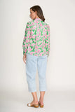 Woman wearing a floral blouse and light blue pants on a white background
