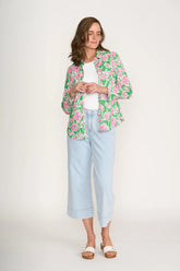 Woman wearing a floral jacket, white shirt, and light blue jeans on a white background