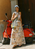Woman in a patterned dress standing next to a red scooter