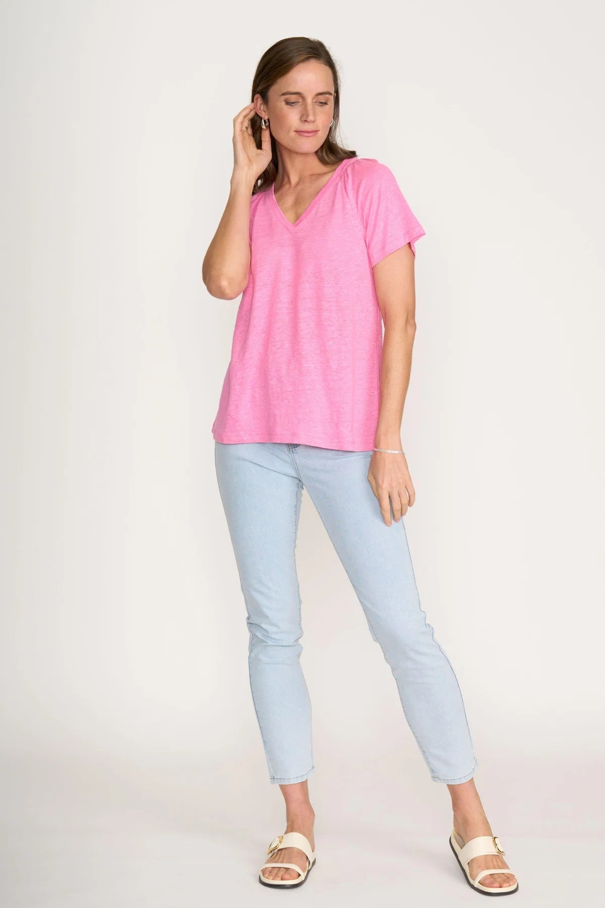 Woman wearing a pink top and light blue jeans on a white background