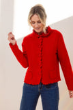 Woman wearing a red jacket and blue jeans against a plain background