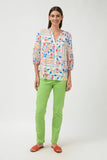 Woman wearing a colorful blouse and green pants on a white background