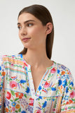 Woman wearing a colorful floral blouse against a white background