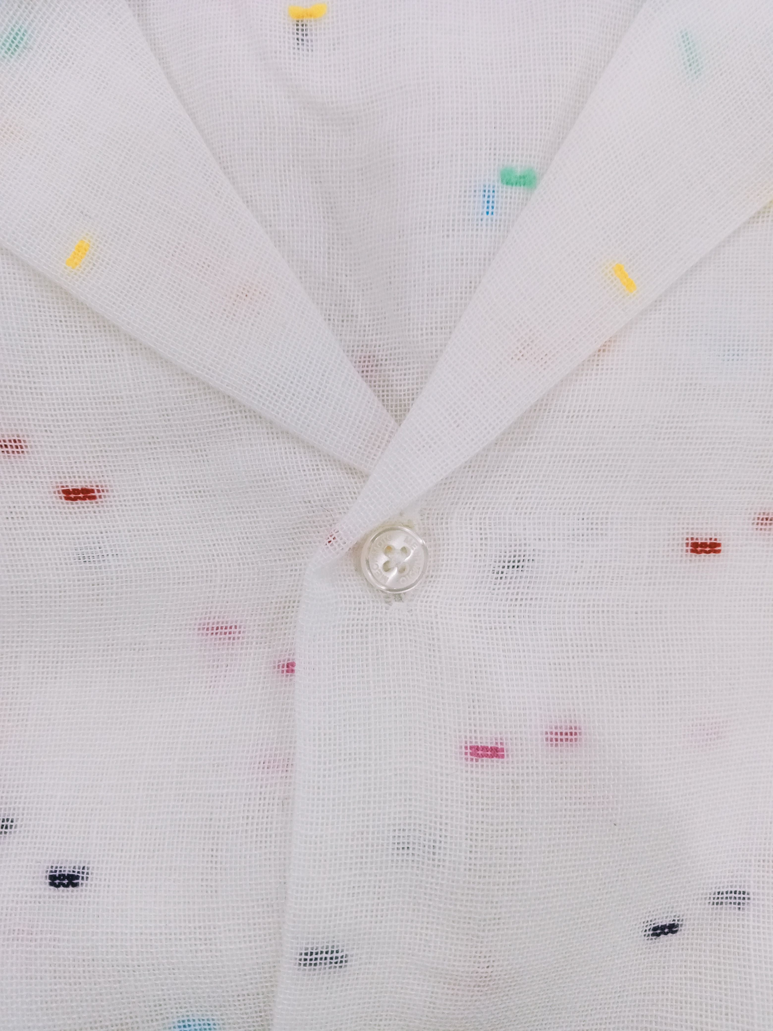 Close-up of a button on a white shirt with small colorful patterns