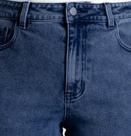 A model wearing a pair of dark blue cropped jeans with a straight-to-slightly-relaxed leg, paired with a white top and beige platform sandals, shot against a light gray studio background.