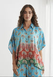A woman modeling a two-piece matching lounge set with a blue and red abstract pattern, shown in a screenshot of a clothing store page.