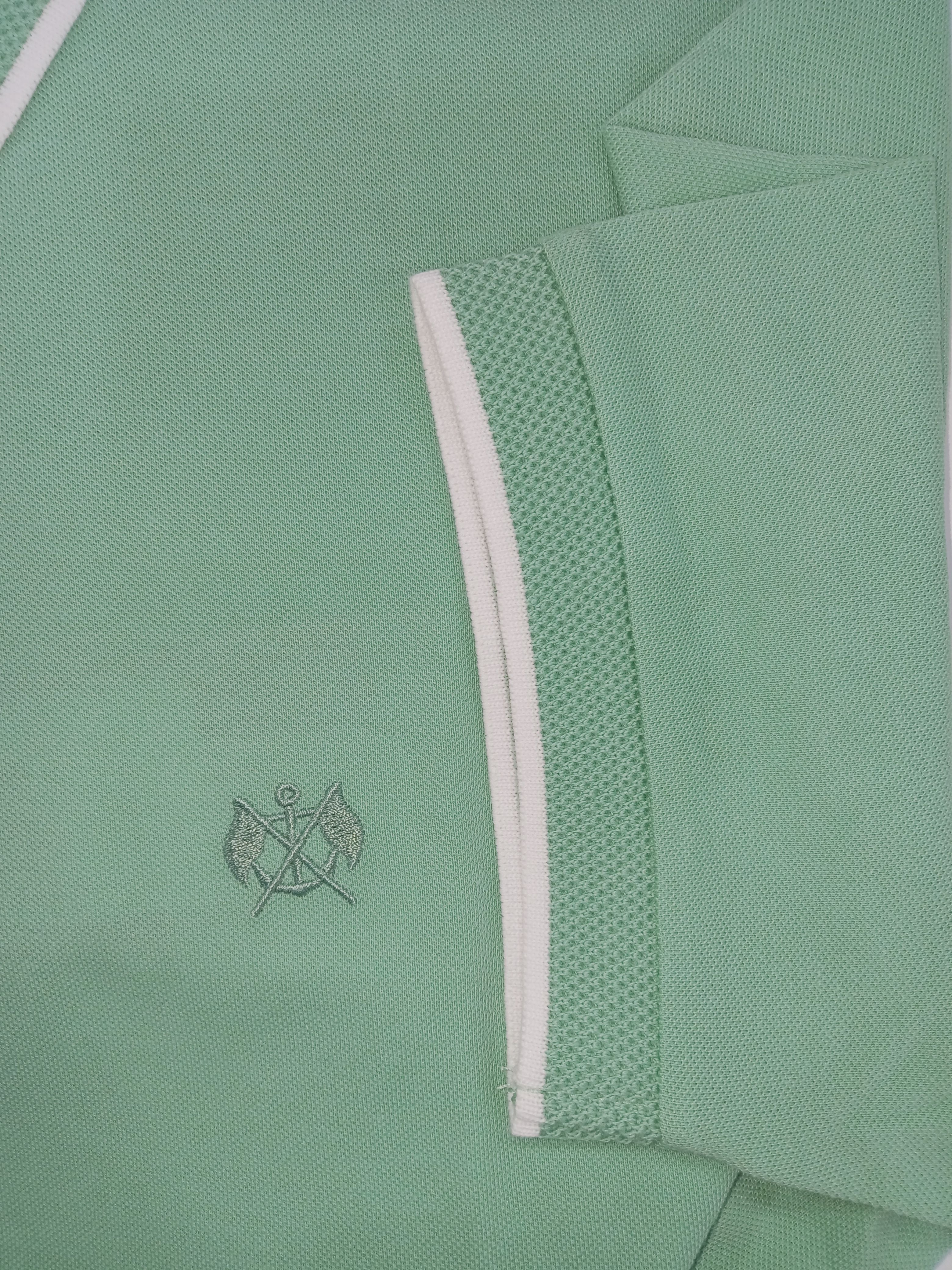 Green polo shirt with a small logo on a light green background