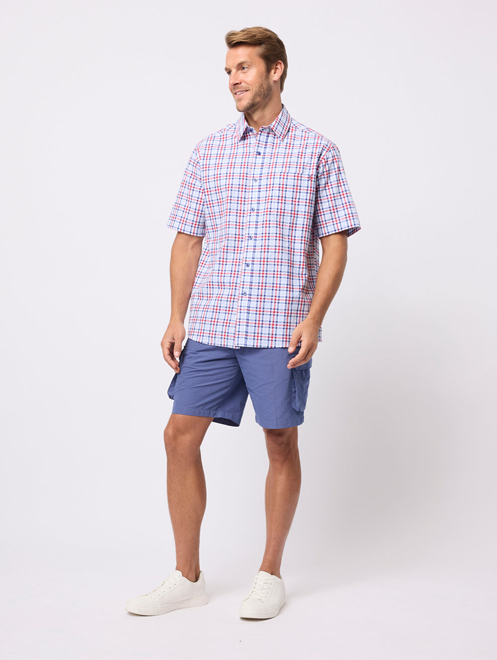 Man wearing a plaid shirt and blue shorts on a white background