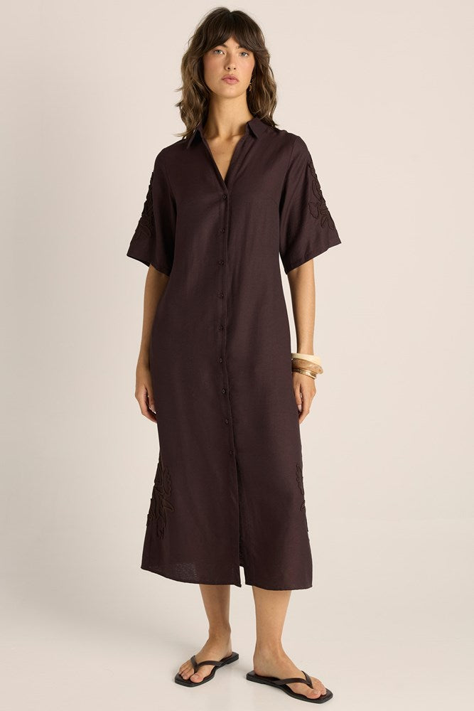 Woman wearing a brown dress against a plain background