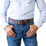 Person wearing a light blue shirt and blue jeans with a brown belt on a white background