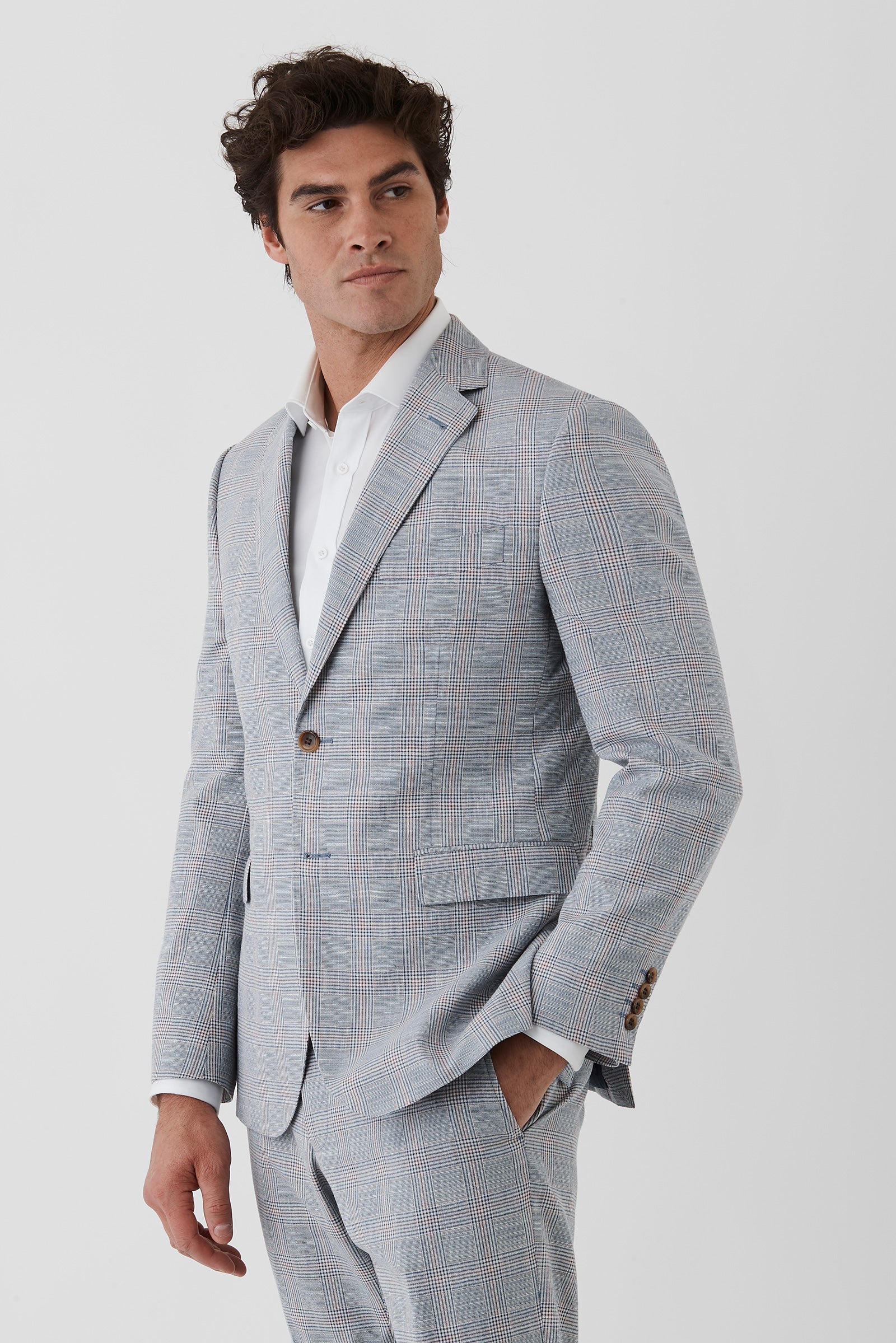 Man wearing a gray checkered suit with a white shirt on a light gray background