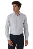 Man wearing a light gray checkered shirt and dark pants on a white background
