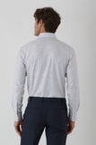 Man wearing a light gray long-sleeve shirt and dark blue pants on a white background