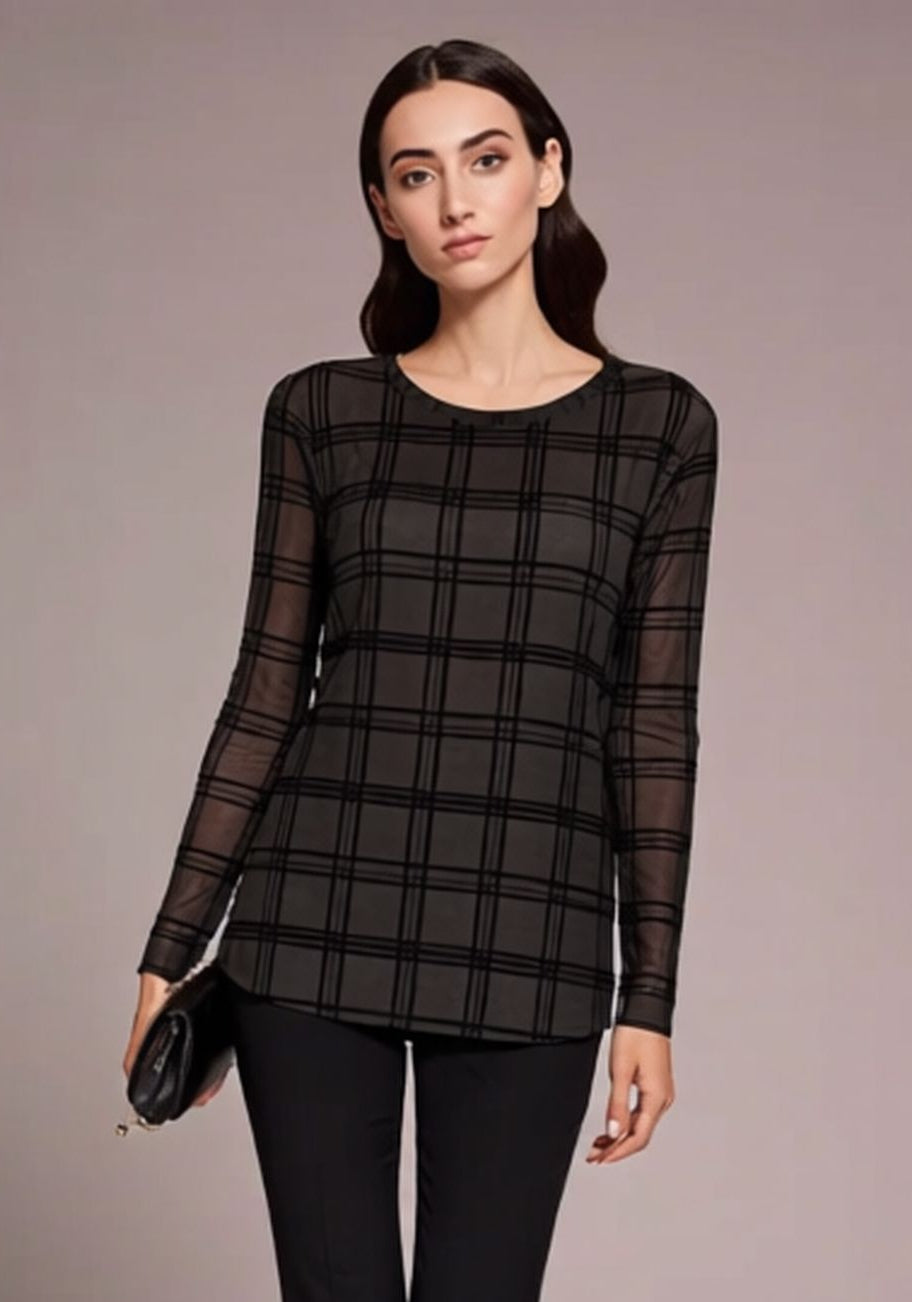 Woman wearing a black plaid top and black pants against a neutral background