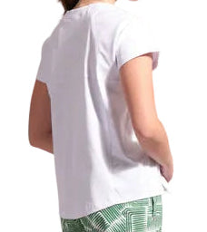 Woman wearing a white t-shirt and green patterned pants against a plain background
