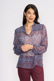 Woman wearing a patterned blouse and maroon pants on a white background