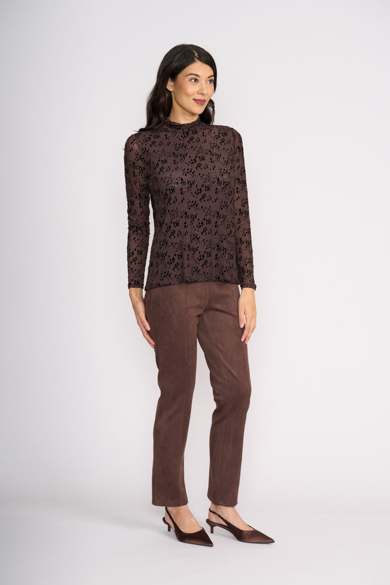 Woman wearing a brown patterned top and brown pants on a white background