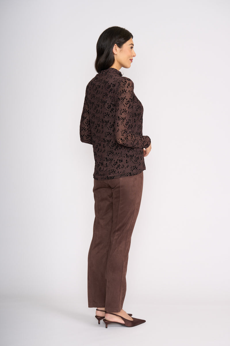 Woman wearing a brown floral blouse and brown pants on a white background