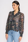 Woman wearing a floral blouse with long sleeves and light blue jeans on a white background