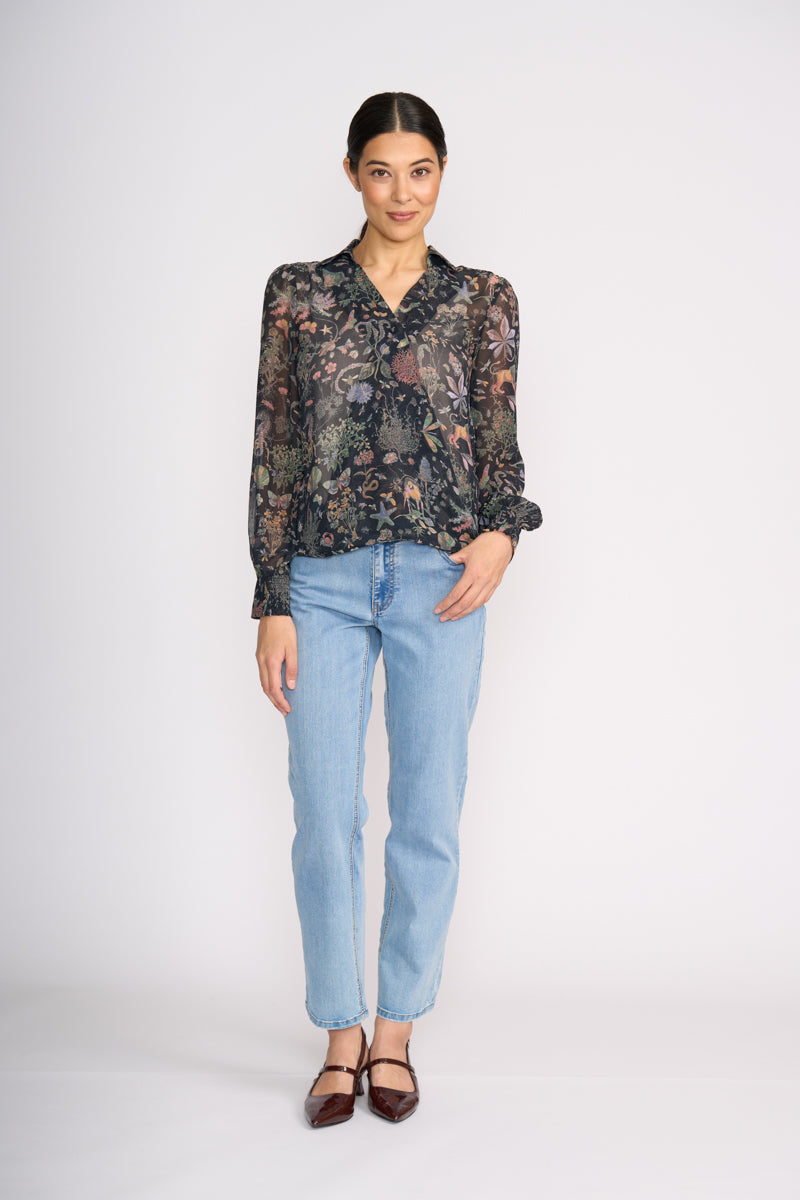 Woman wearing a floral blouse and light blue jeans on a white background