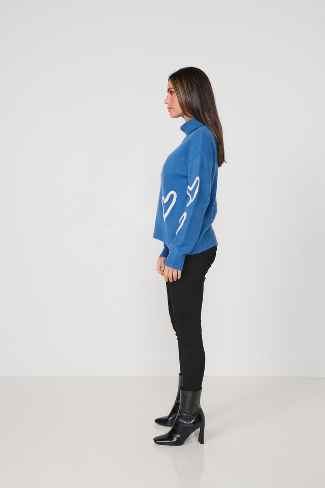 Woman wearing a blue sweater with white heart designs on a white background