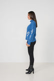 Woman wearing a blue sweater with white heart designs on a white background