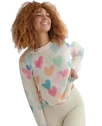 Woman wearing a colorful heart-patterned sweater against a white curtain background