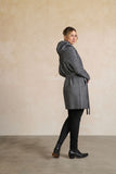 Woman wearing a gray patterned coat against a beige wall