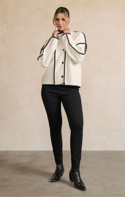 Woman wearing a white and black outfit against a beige background