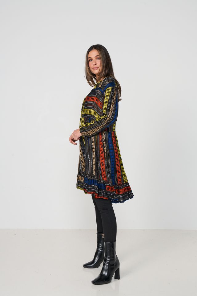 Woman wearing a colorful patterned dress with black boots on a white background